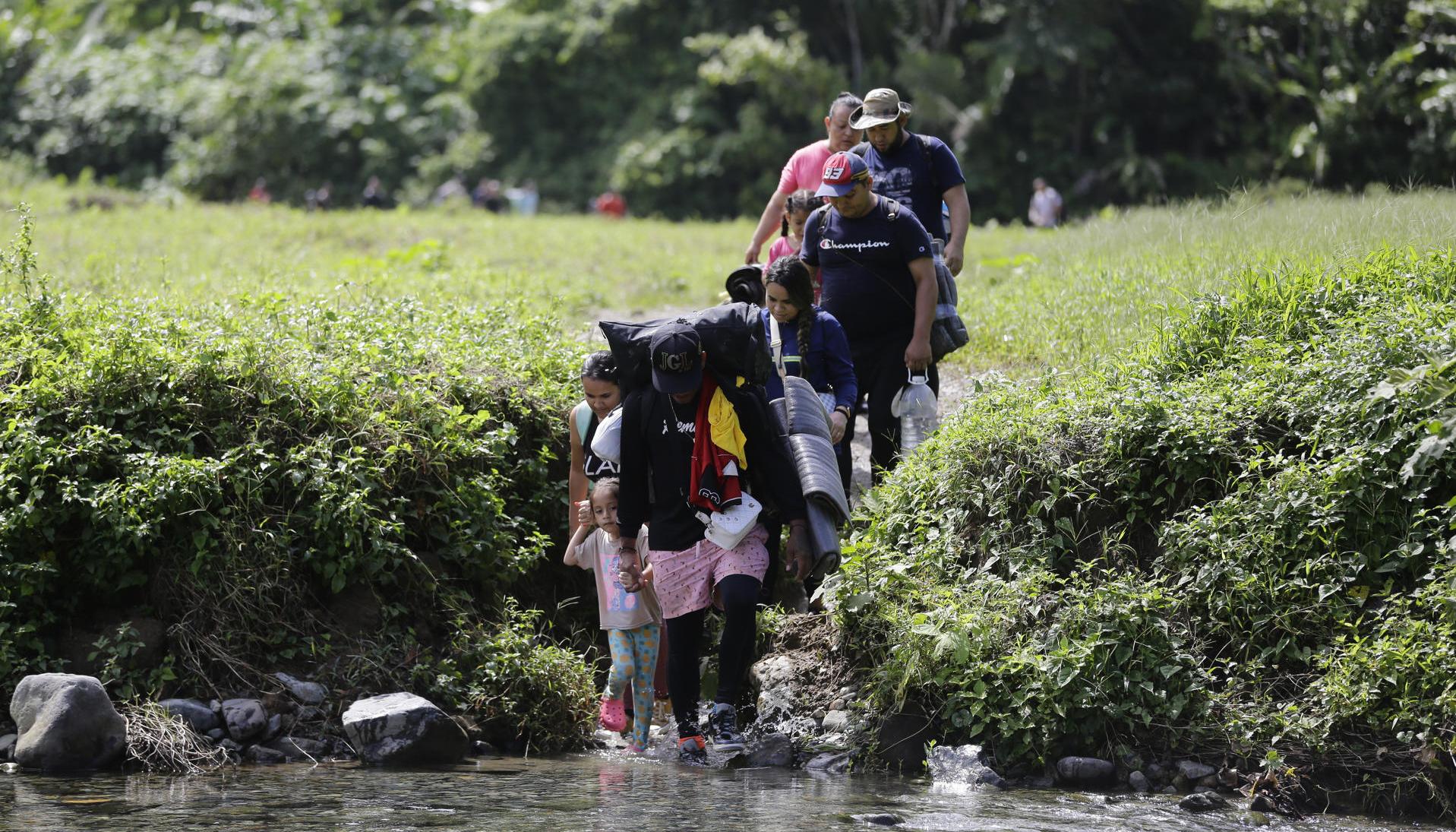  Migrantes acompañados con niños pequeños mientras caminan el Darién