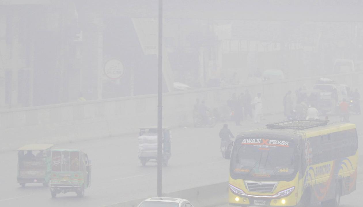 Personas viajan en automóviles y motocicletas bajo una nube de contaminación en Lahore (Pakistán)