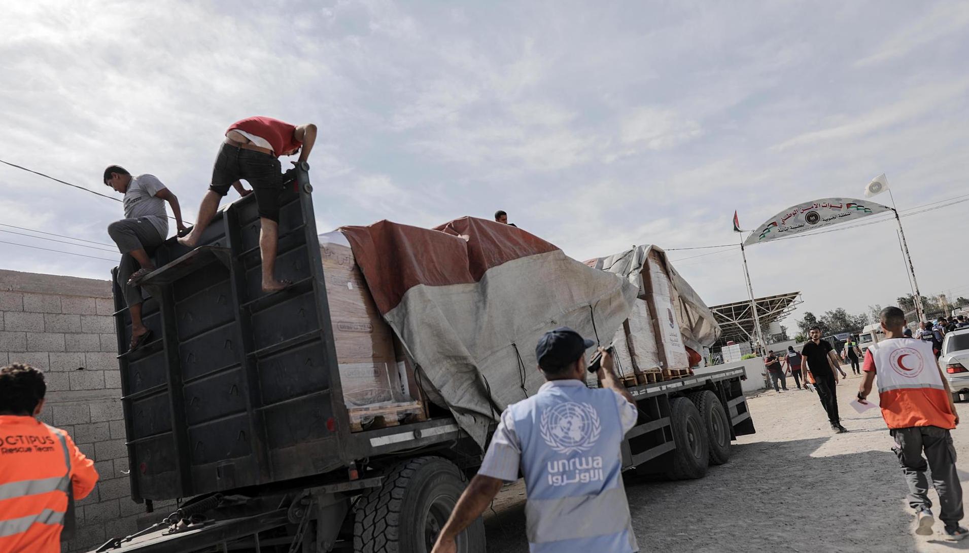 Funcionarios de la Media Luna Roja palestina ayudan a descargar la ayuda para la Franja de Gaza