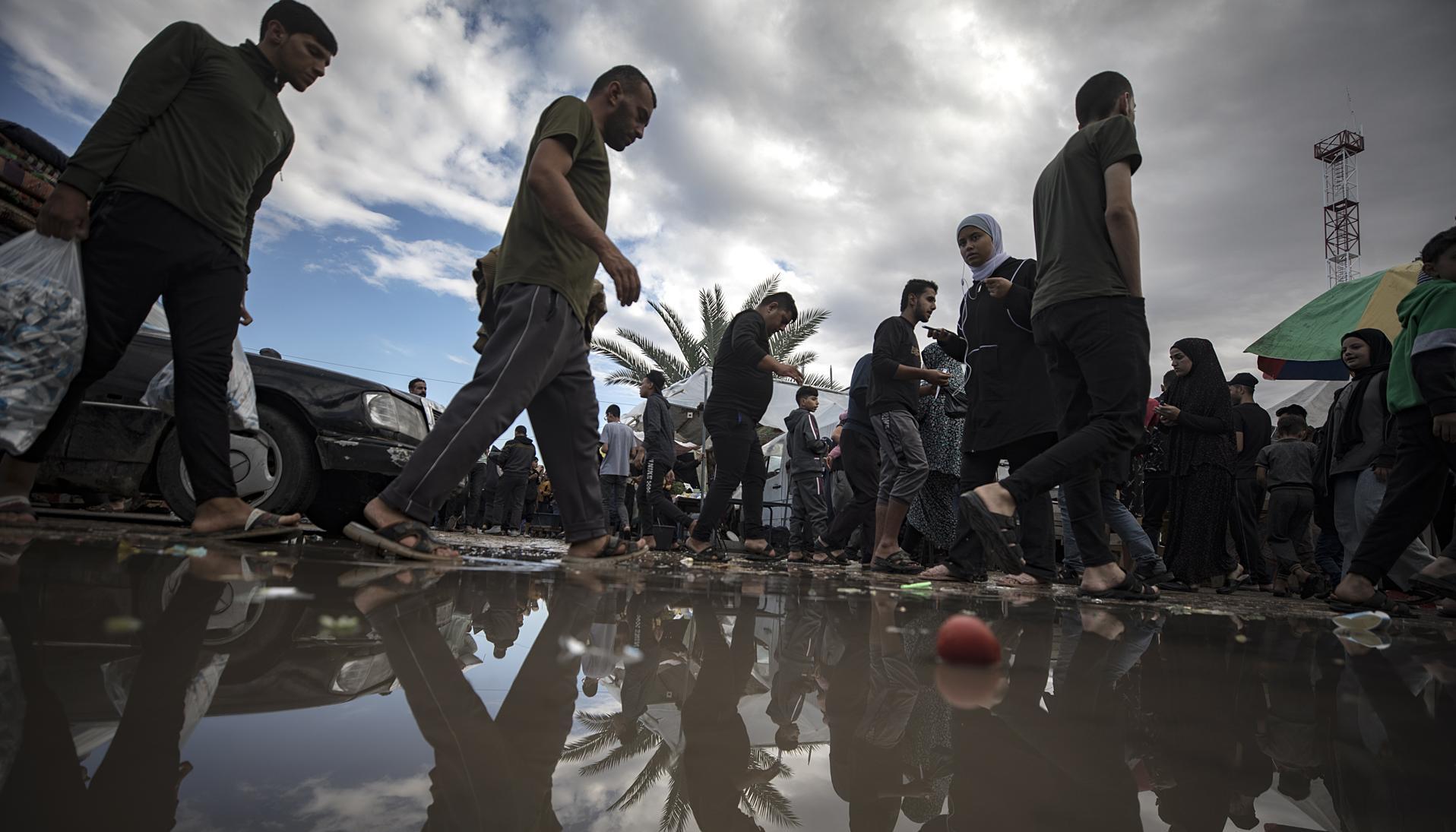 Los palestinos pasan junto a un charco de agua después de una noche lluviosa.