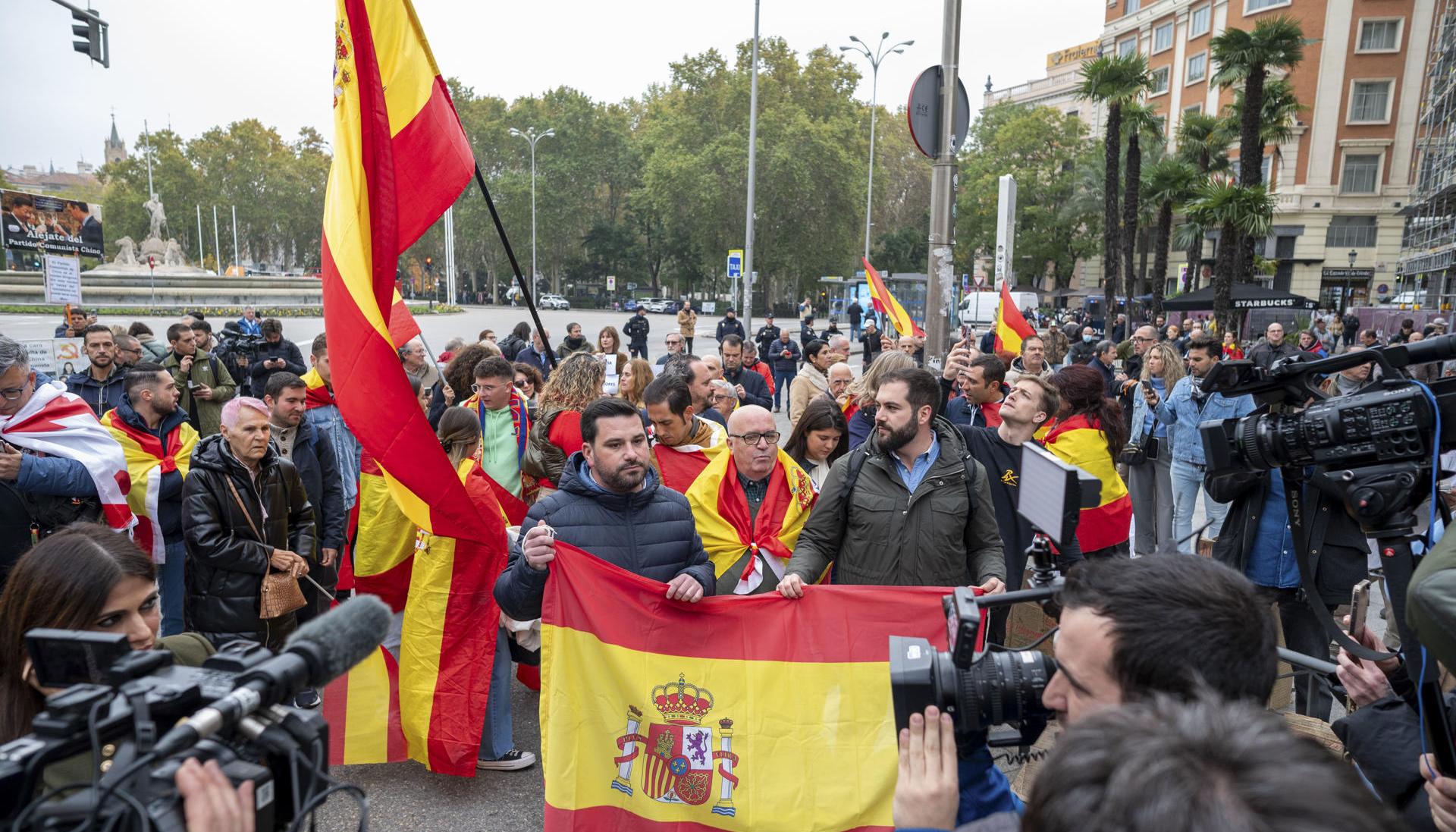 Varias personas con banderas de España protestan en las inmediaciones del Congreso de los Diputados