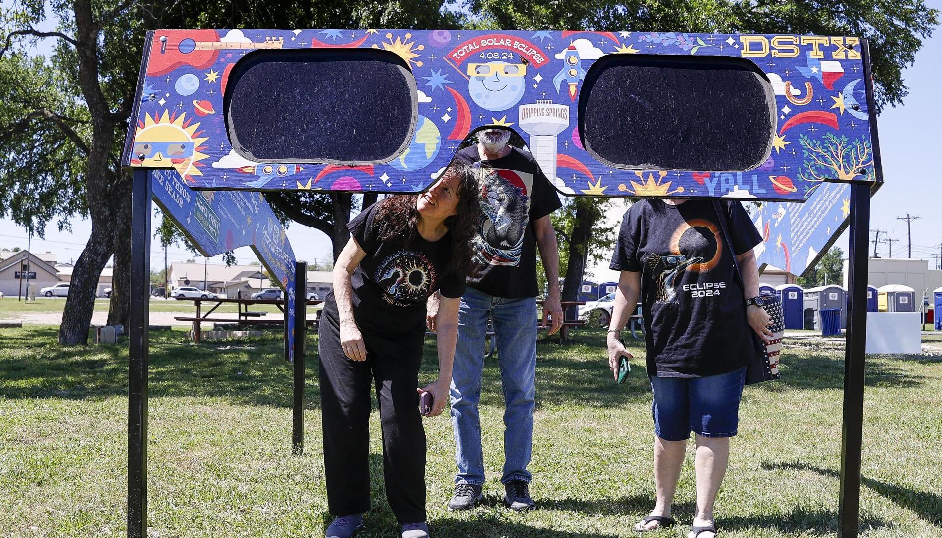Una familia mira a través de un par de gafas gigantes especiales para el eclipse solar en el Veterans Memorial Park en Dripping Springs, Texas