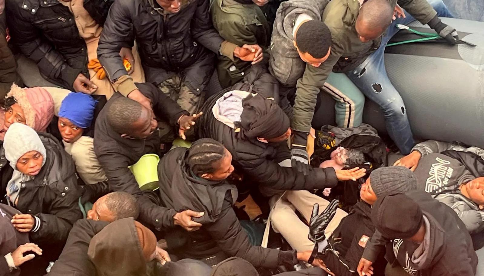 Foto del recién nacido rodeado de hombres y mujeres apiñados en la lancha. 