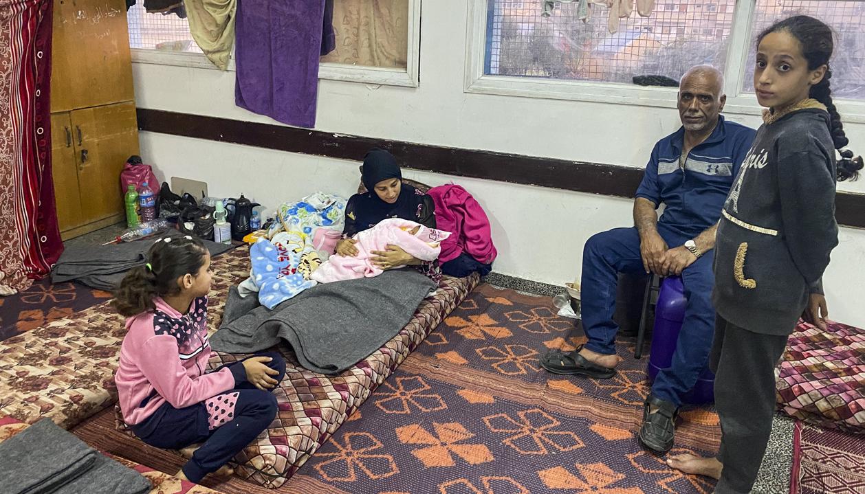 Imagen de una joven palestina refugiada junto a su bebé en una escuela de Rafah.