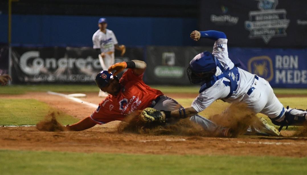 Jordan Díaz, de Caimanes, es puesto out en la goma por Daniel Vellojín, receptor de Vaqueros. 