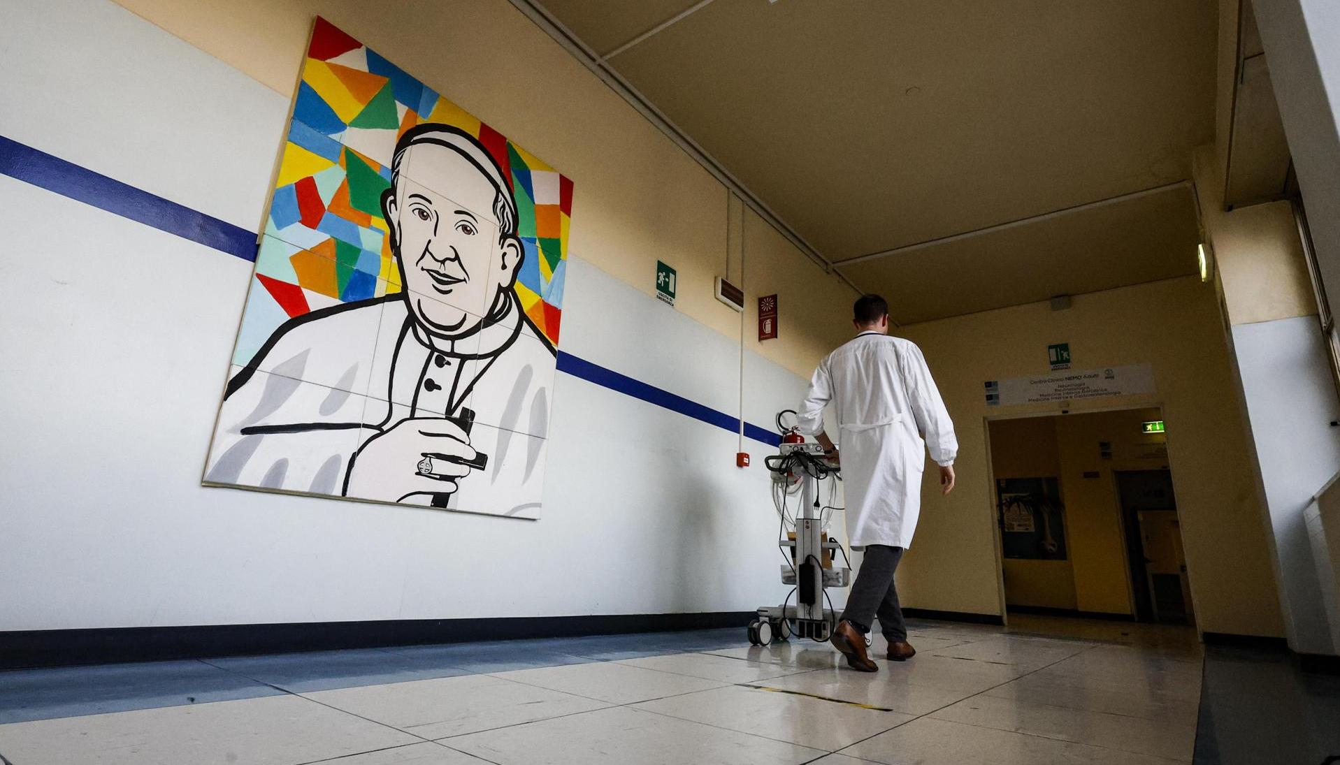 Un médico pasa junto a un mural que representa al Papa Francisco dentro del Hospital Gemelli.