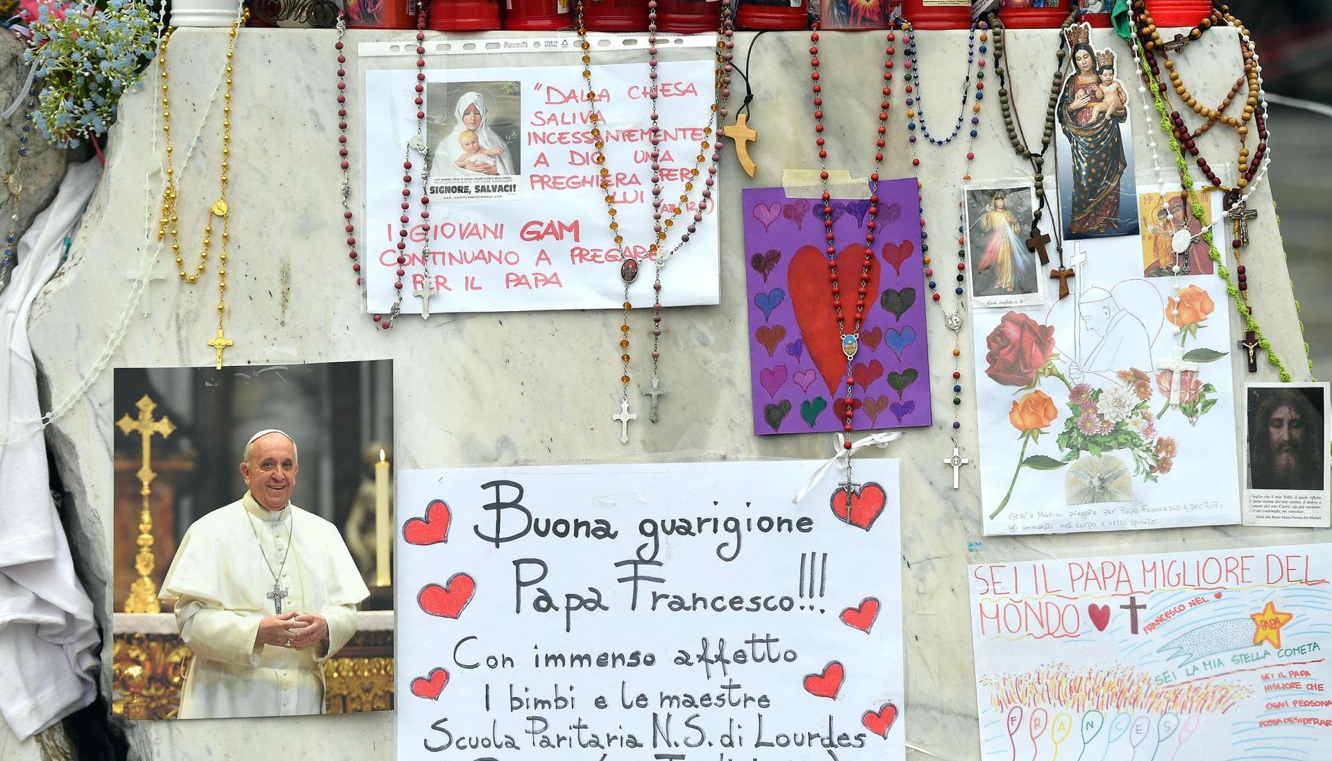 Velas, rosarios y mensajes de apoyo al Papa Francisco se exhiben en la estatua del papa Juan Pablo II junto al Hospital Universitario Gemelli, donde está hospitalizado.