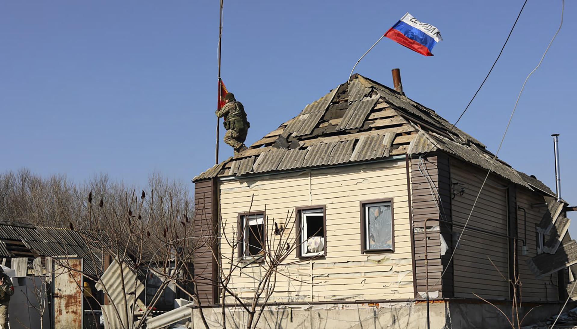 Un soldado ruso instalando una bandera roja en el techo.