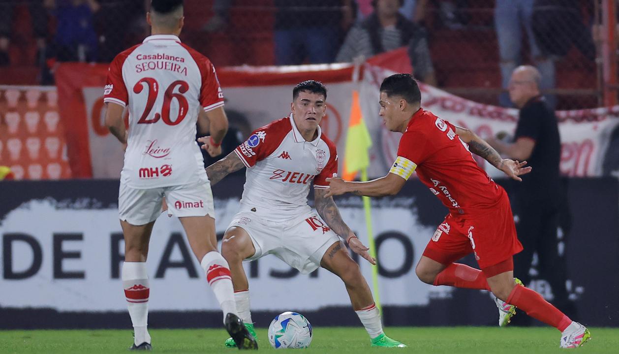 Juan Fernando Quintero intenta avanzar ante la marca de Rodrigo Cabral, de Huracán.
