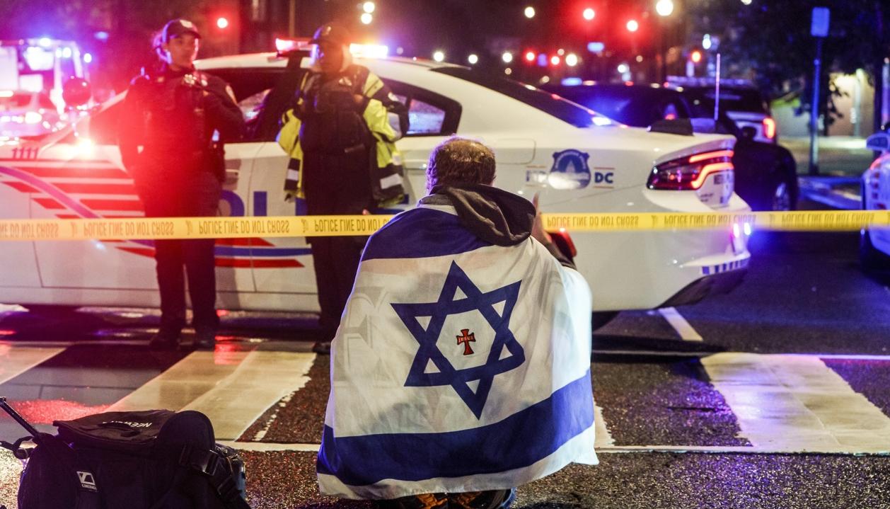 Un hombre con una bandera israelí en el lugar de los hechos.