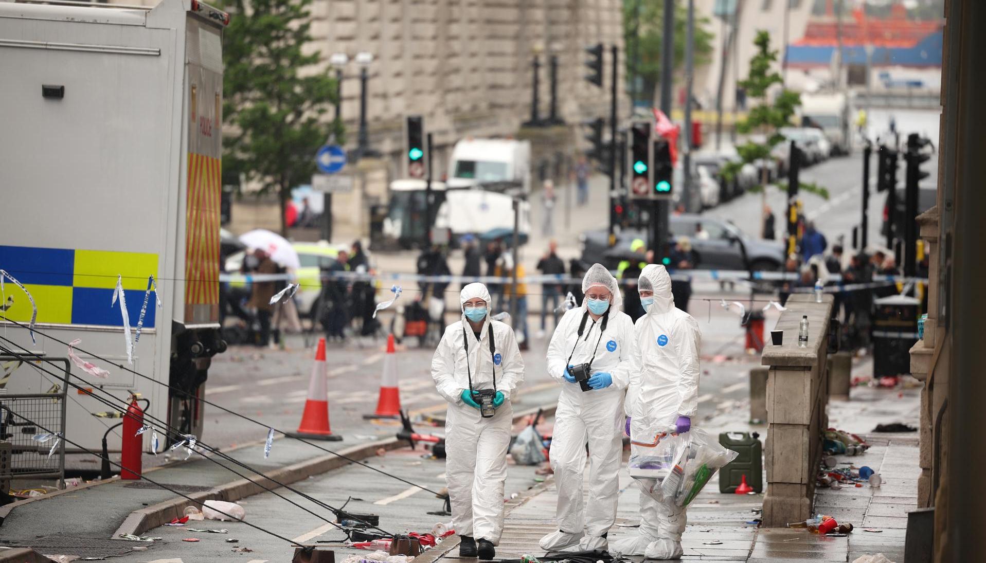Oficiales forenses en el lugar donde un carro colisionó con personas durante el desfile del trofeo del Liverpool FC.