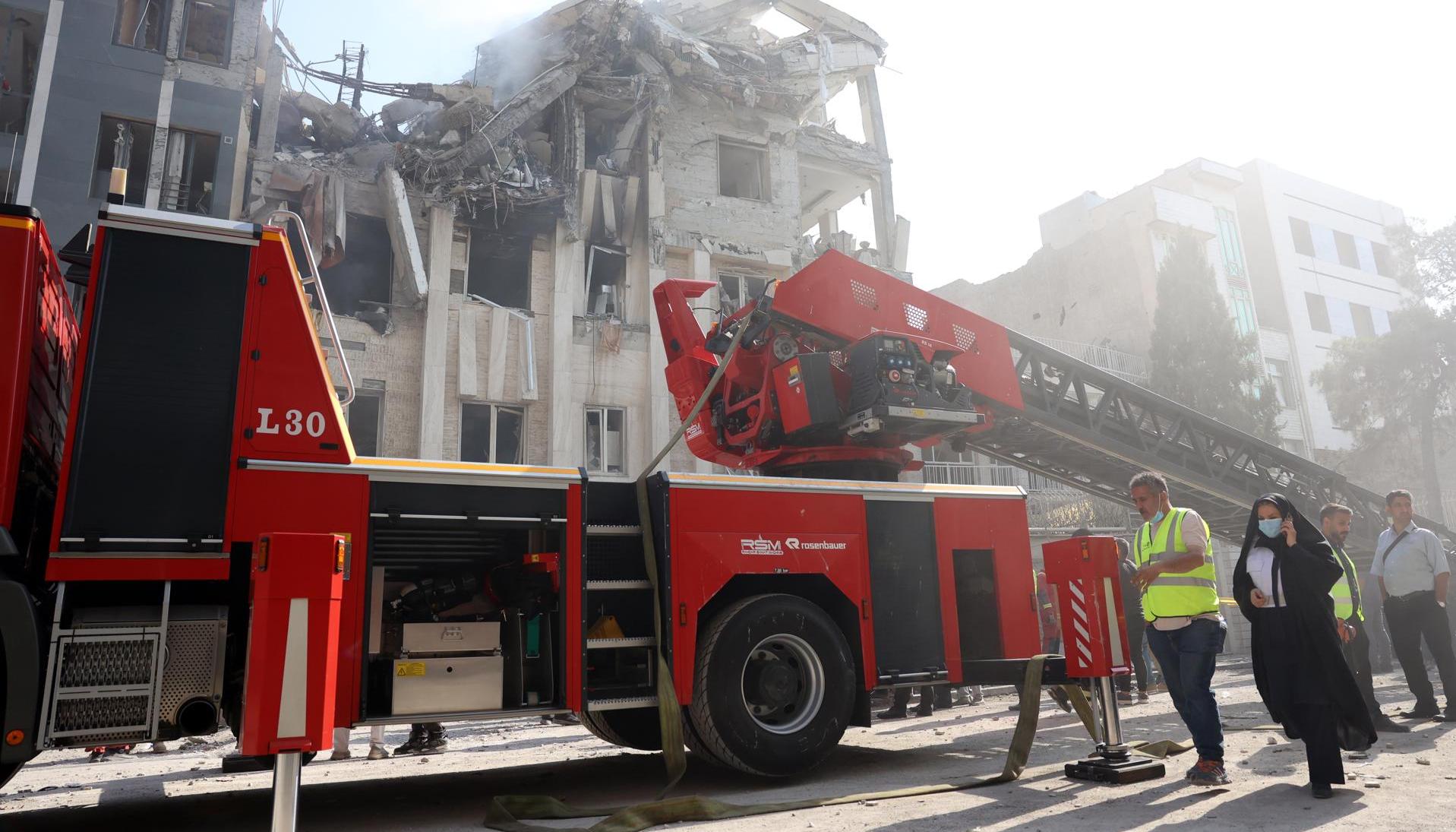 Los bomberos trabajan en un edificio alcanzado por ataques aéreos israelíes en el centro de Teherán.