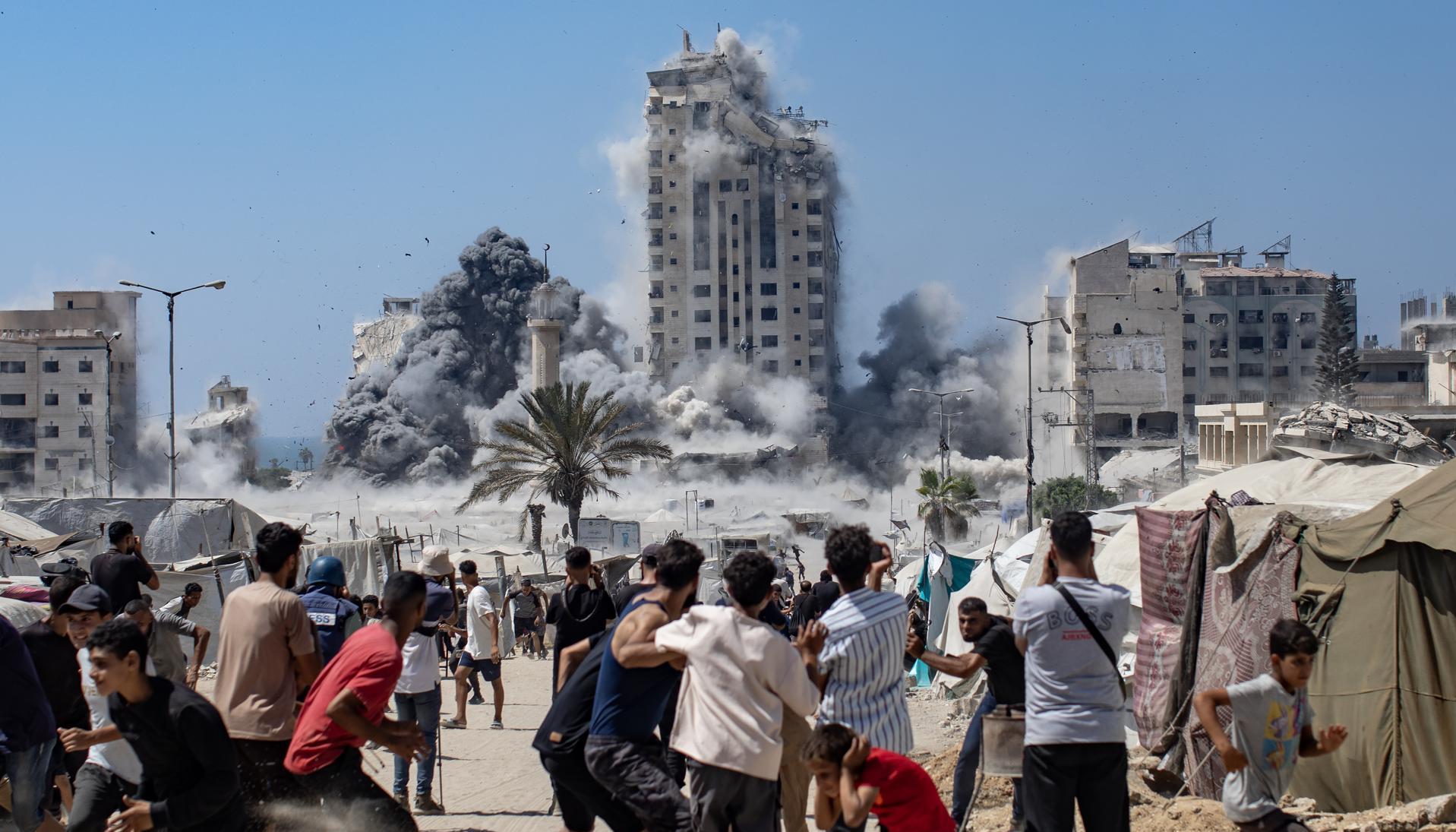 Ciudadanos palestinos reaccionan al humo que se eleva desde la Torre Mushtaha tras un ataque aéreo israelí.