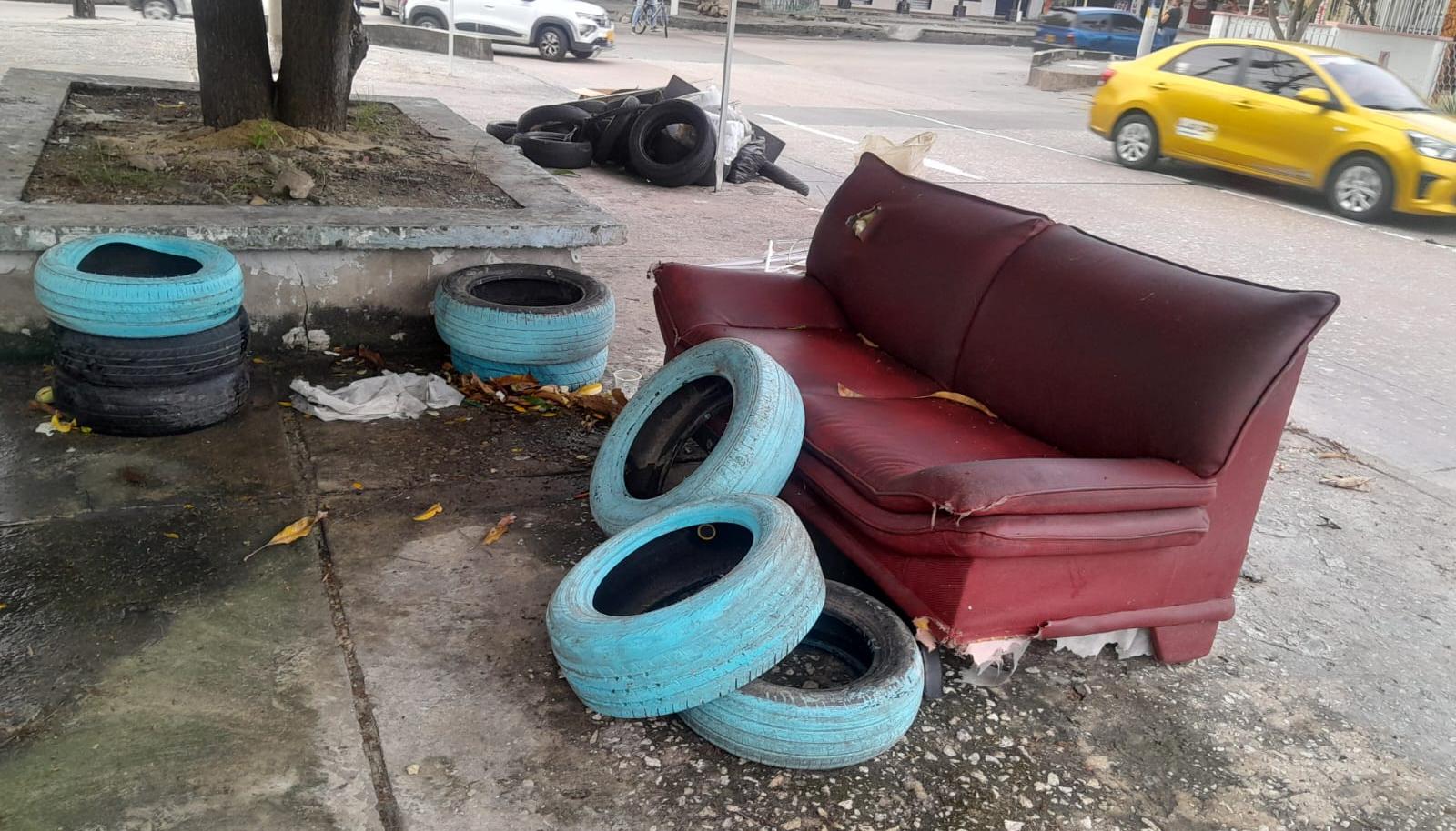 Llantas y un sofá abandonado frente al colegio. 