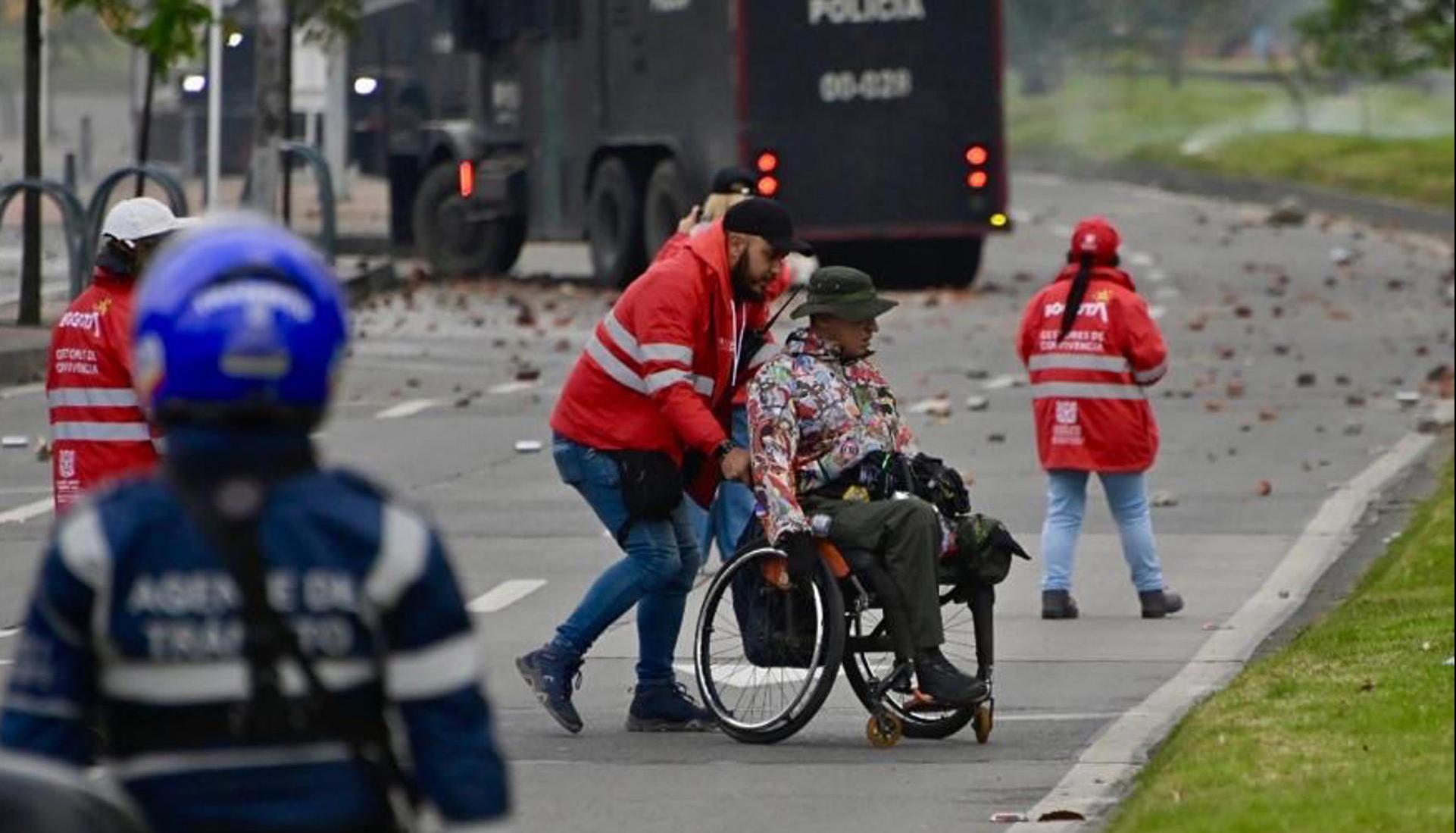 Gestor de convivencia acompañando a una persona en silla de ruedas este viernes, durante protesta en Bogotá.