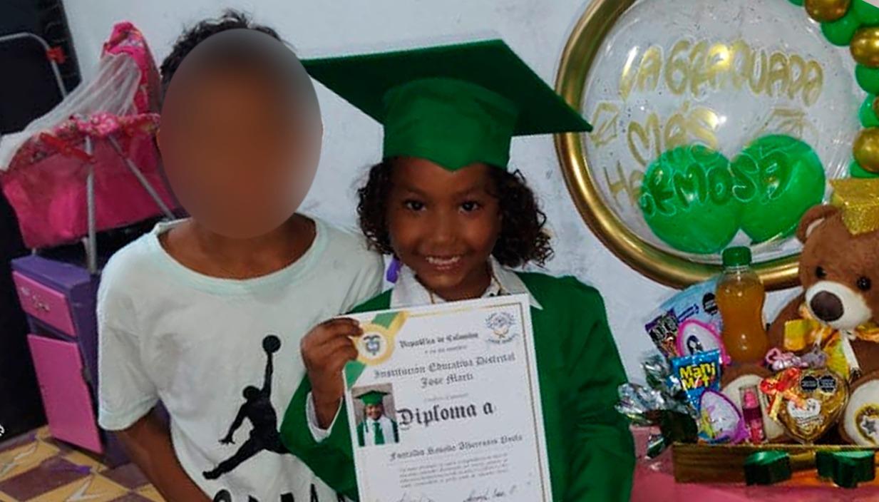 La niña con su diploma de grado y al lado de su hermanito