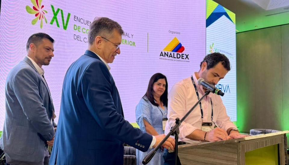 Hebert Mantilla, director de Comfamiliar Atlántico, firmando el convenio. A su lado, Javier Díaz, de Analdex.