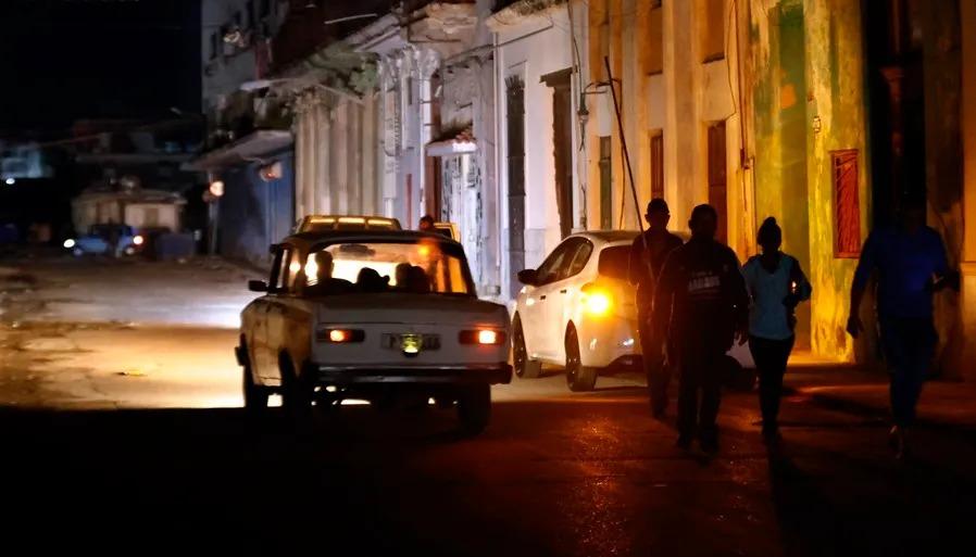 Personas caminan por un sector sin servicio eléctrico en La Habana. 