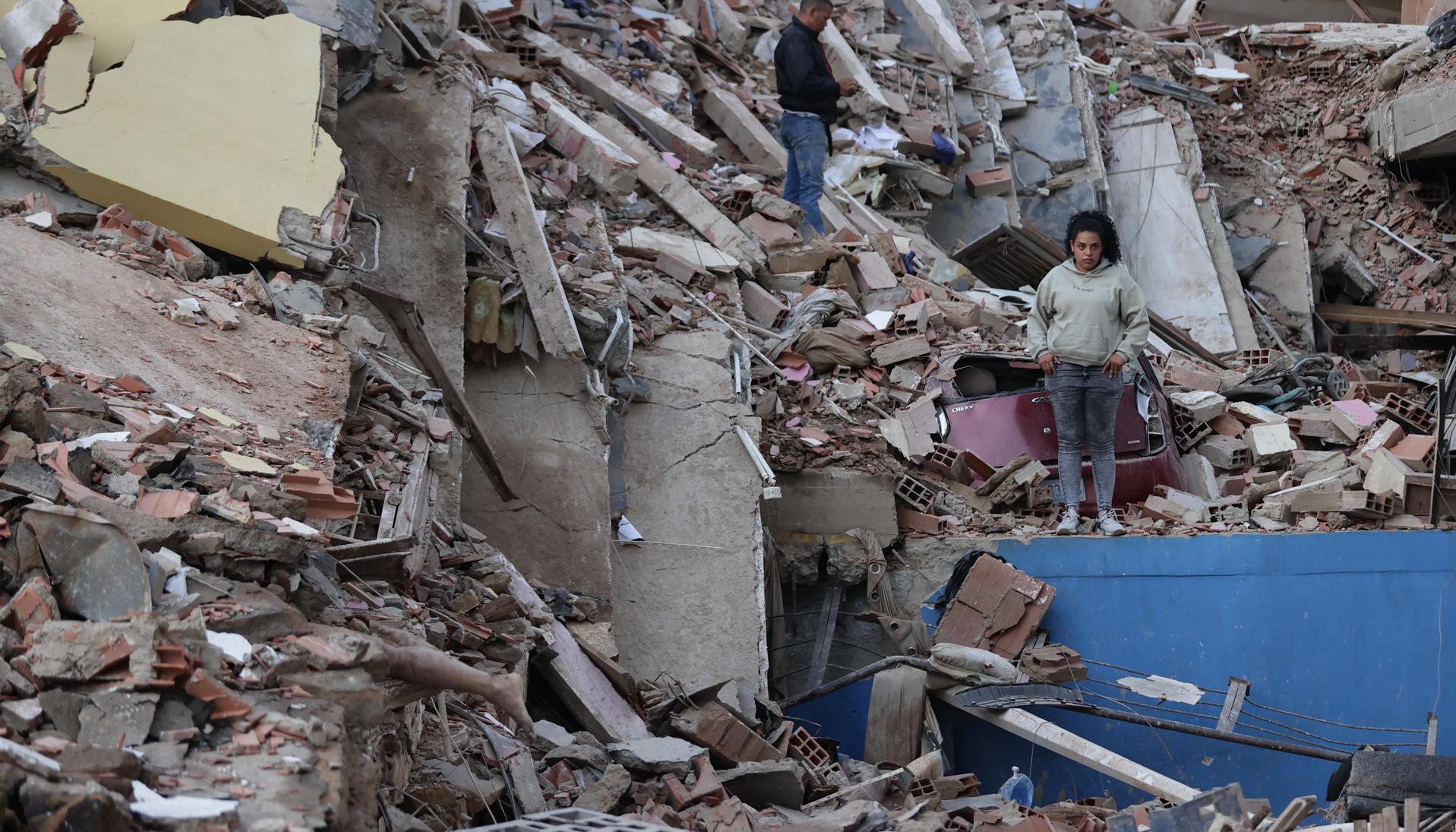 Residentes caminan entre los escombros de edificios derrumbados por los terremotos, en la localidad de Catia La Mar, en La Guaira.