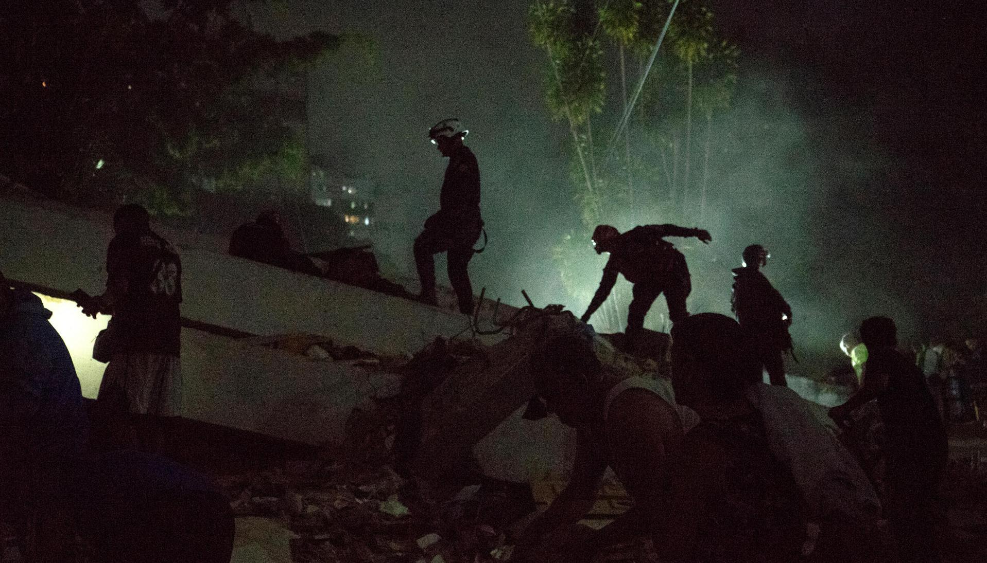  Integrantes de cuerpos de emergencia buscan víctimas entre escombros