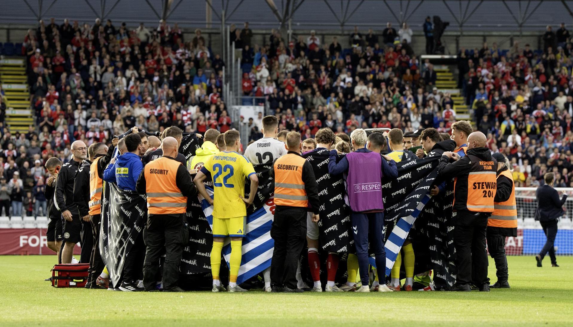 Jugadores de Dinamarca y Ucrania alrededor de Christian Eriksen después de que se desplomara.