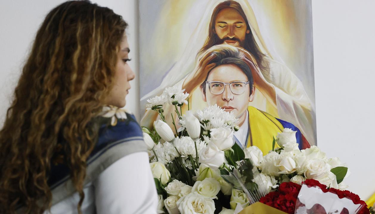Una persona pone flores en un altar durante la conmemoración del primer aniversario del atentado contra Miguel Uribe Turbay en Bogotá.