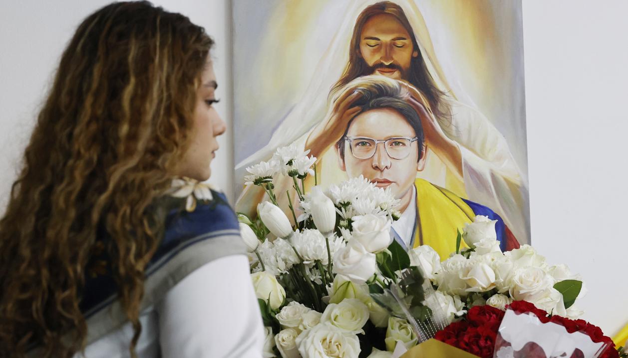 Una persona pone flores en un altar durante la conmemoración del primer aniversario del atentado contra Miguel Uribe Turbay en Bogotá.