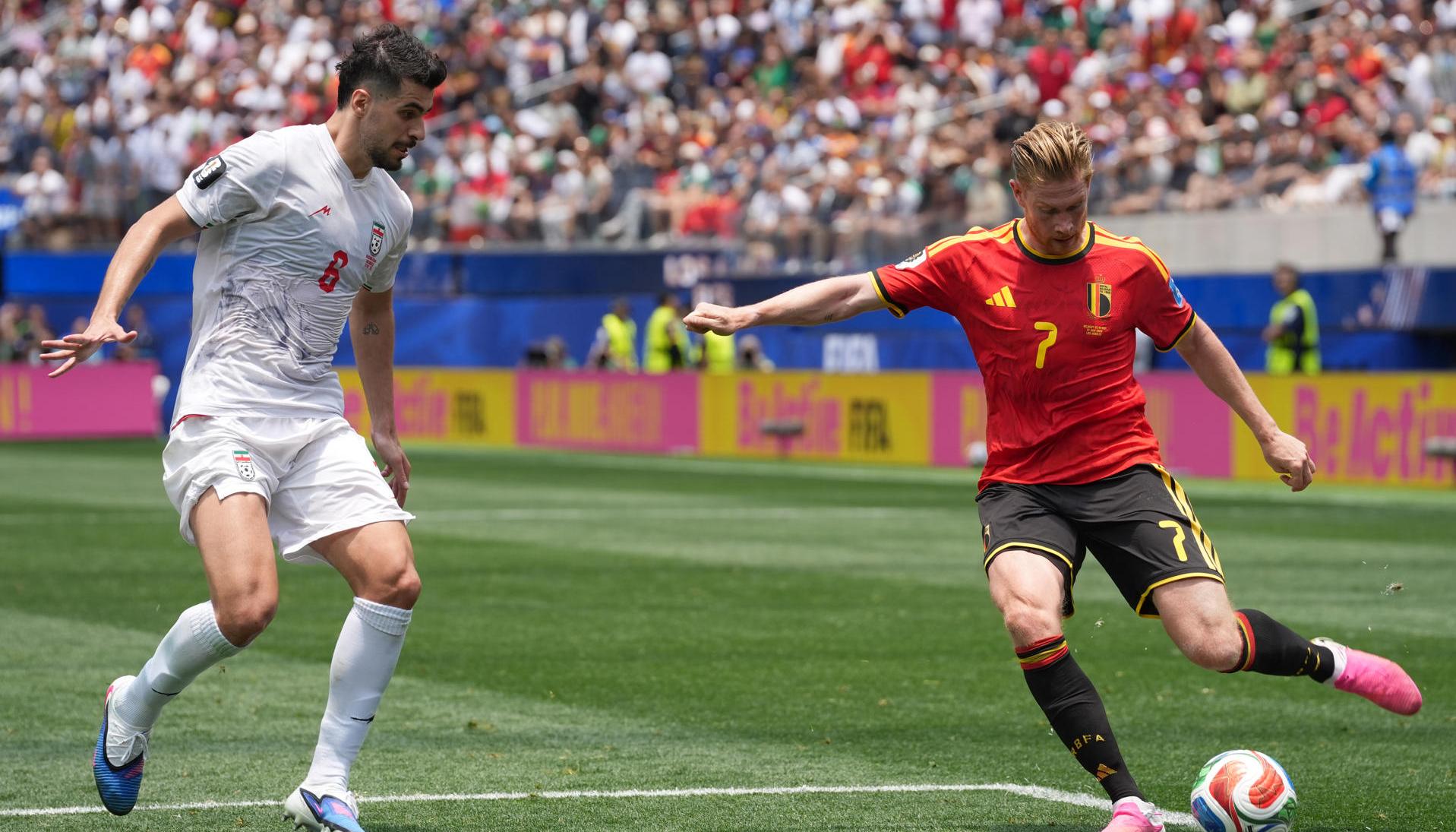 Kevin De Bruyne, de Bélgica, disputa el balón con Saeid Ezatolahi, de Irán.