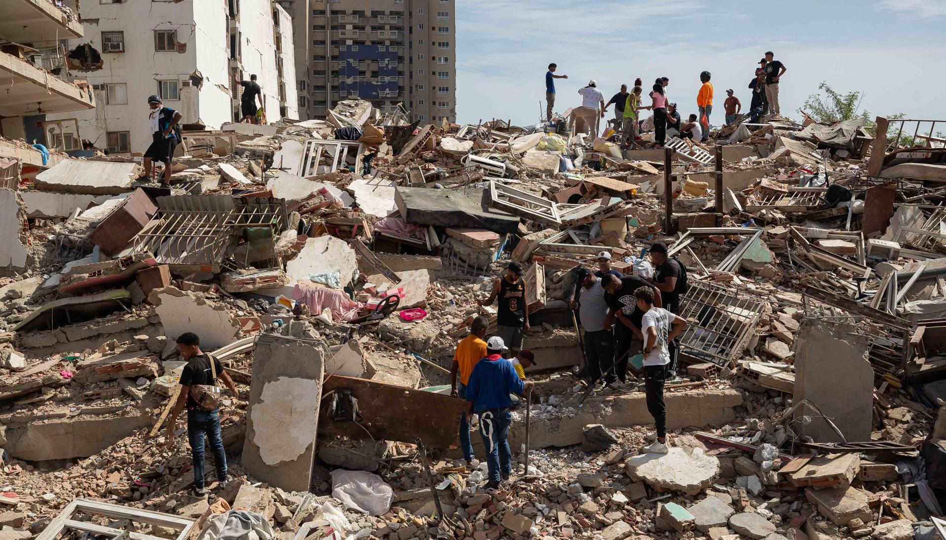 Personas caminan entre escombros de edificios afectado por terremotos