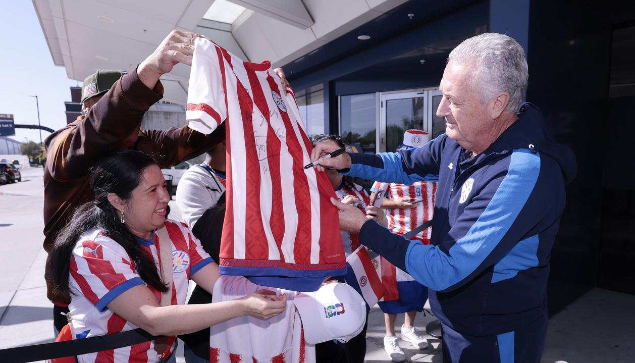 Gustavo Alfaro, técnico de Paraguay, firma camisetas a los aficionados.