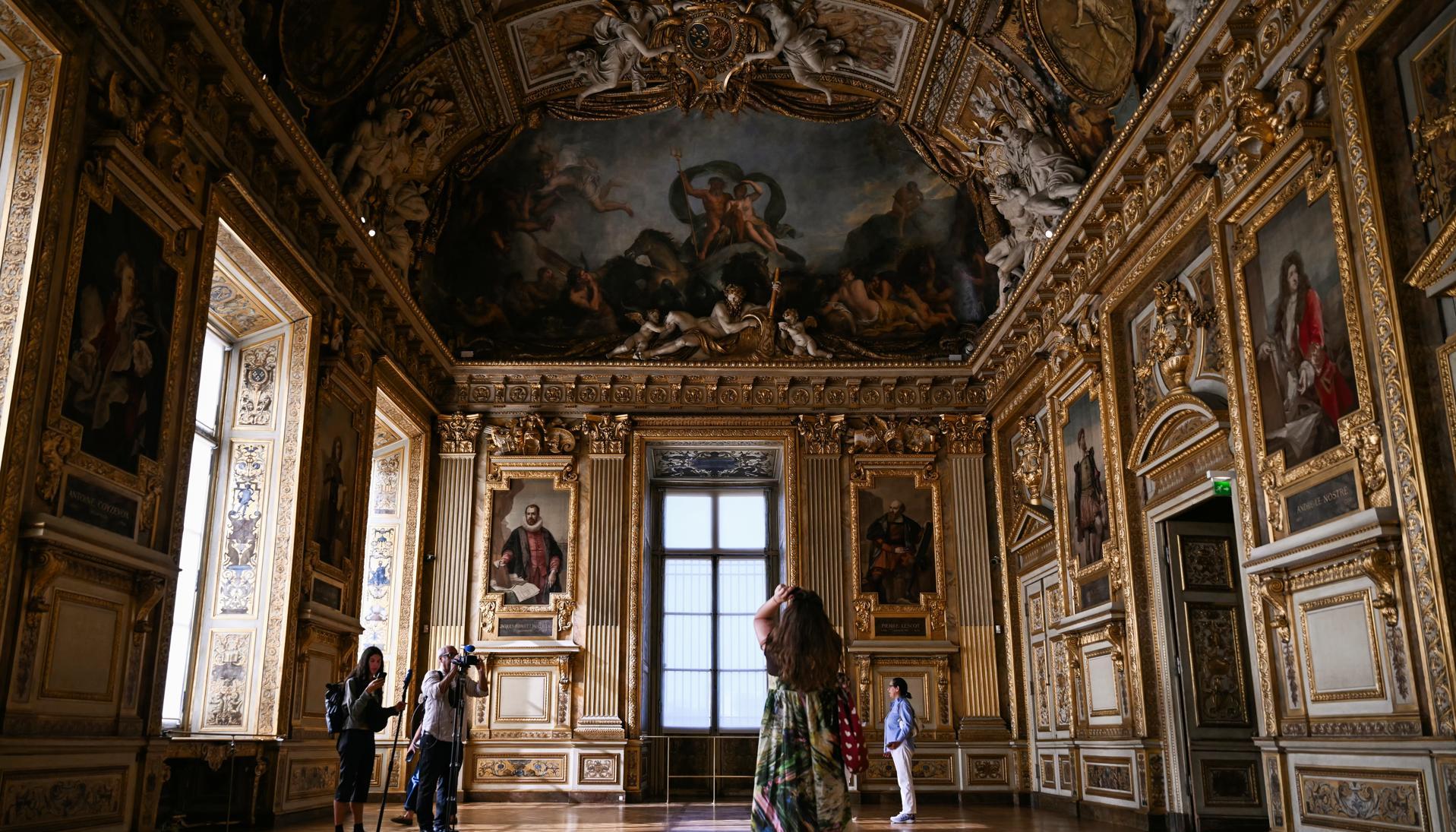 Un grupo de personas recorre la Galería Apolo del Museo del Louvre.