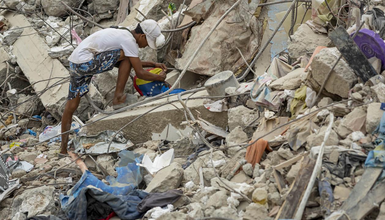 Una persona busca entre los escombros de edificios destruidos por terremotos.
