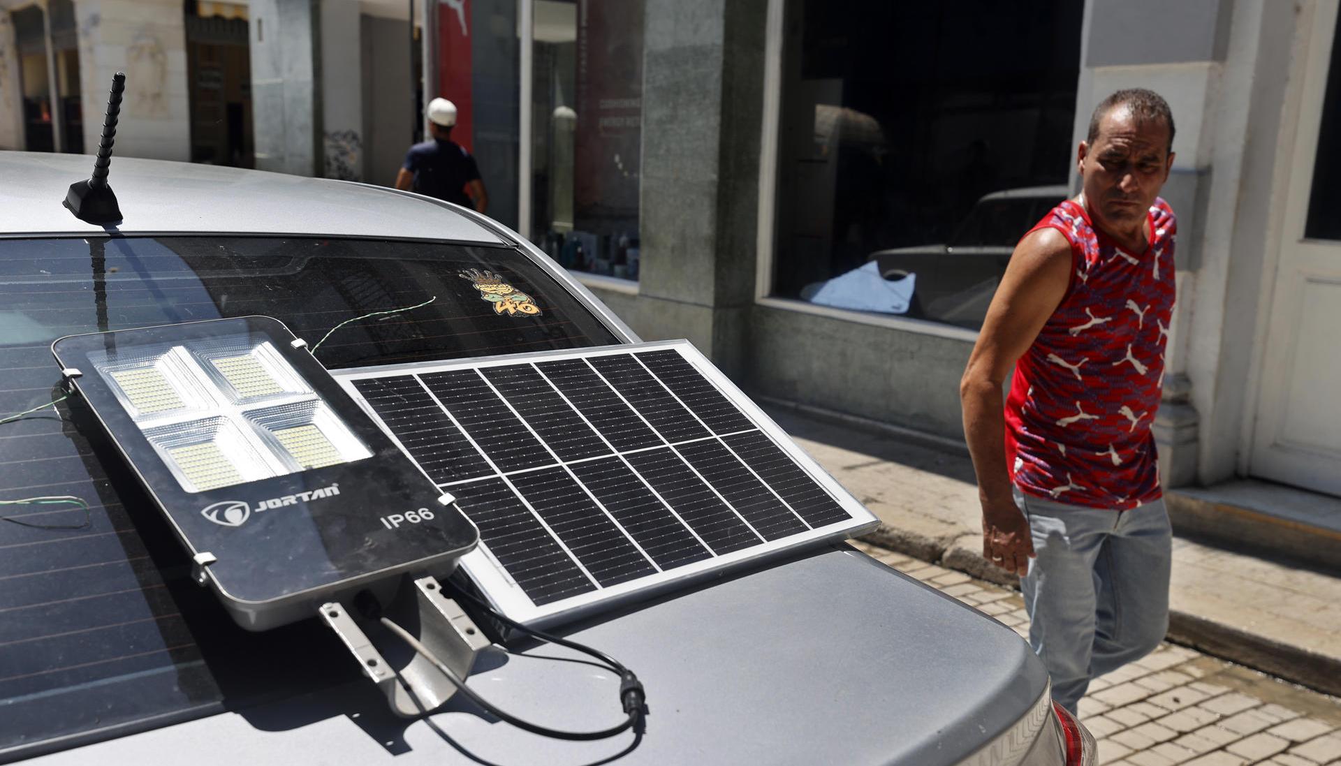Hombre observa un panel solar que suministra energía a una lámpara.
