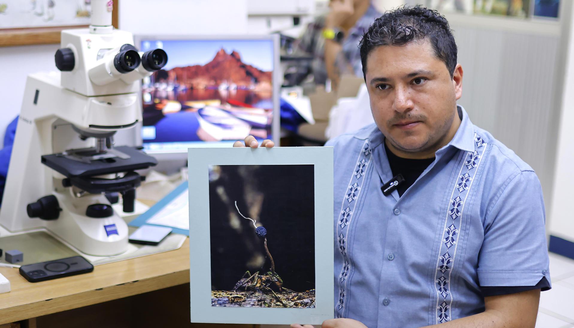 Un maestro en ciencias muestra una fotografía de una hormiga infectada.