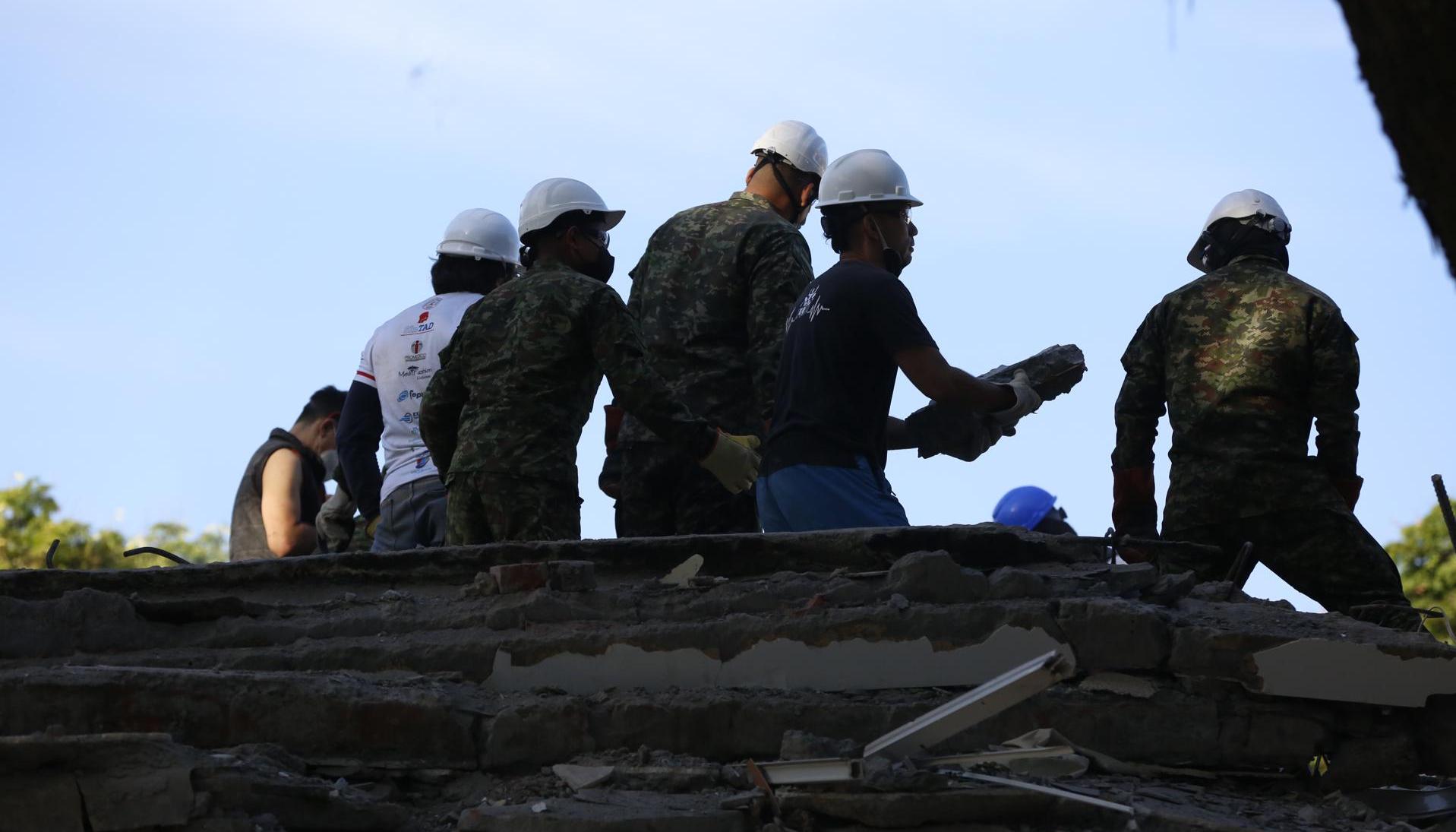 Integrantes de organismos de socorro buscan personas desaparecidas en los escombros.