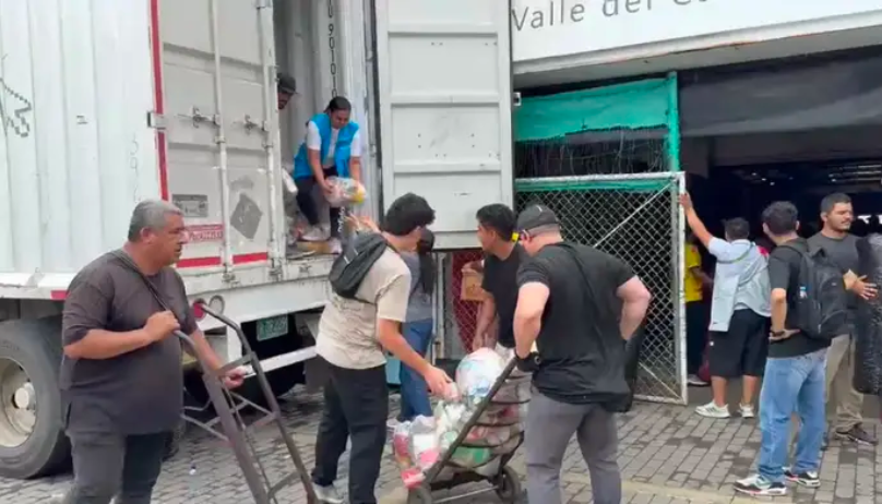 Miembros de la comunidad descargan una de las tractomulas con ayuda humanitaria. 