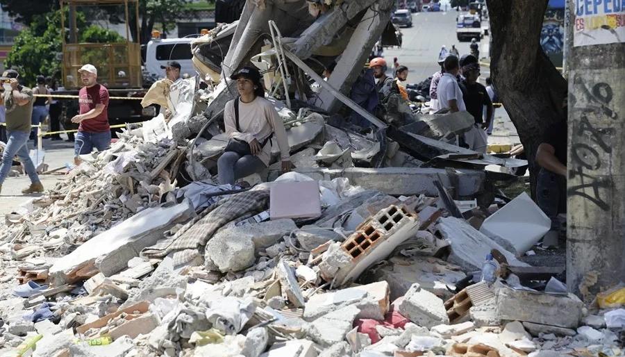 Una mujer espera entre los escombros de un edificio tras el terremoto de magnitud que sacudió a Pereira.