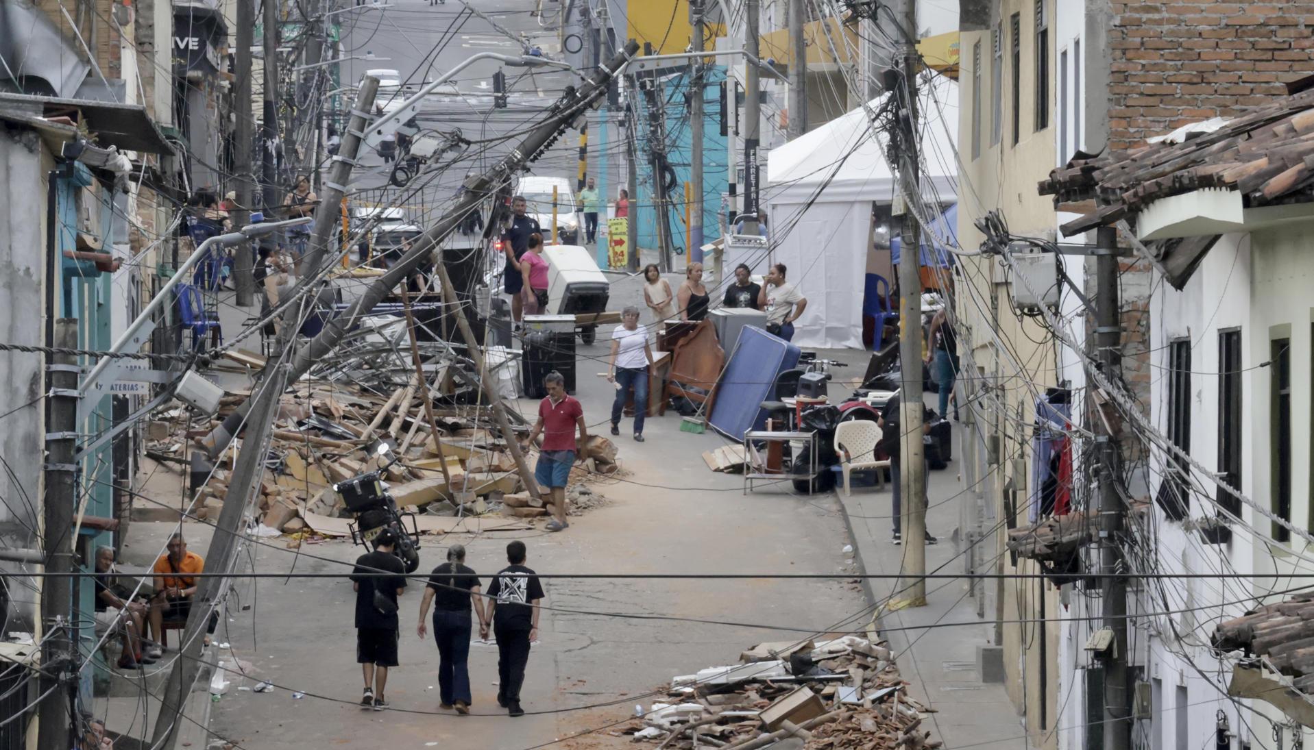 Personas caminan frente a edificaciones afectadas por el terremoto en Pereira.