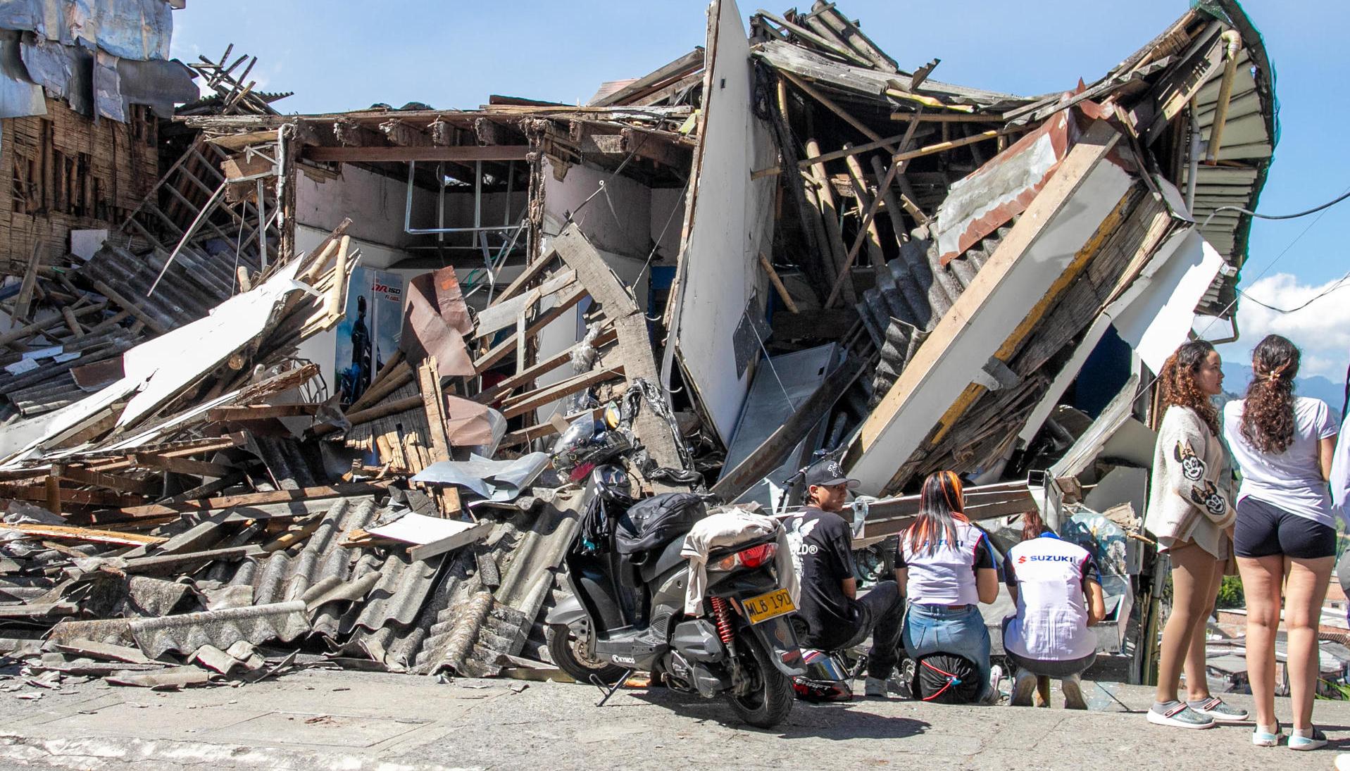 Personas observan una edificación destruida por un terremoto en Manizales