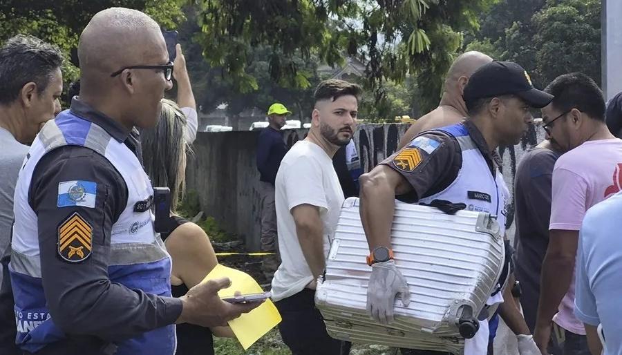 Policía transporta una maleta recuperada en el lugar donde ocurrió el accidente de dos helicóptero