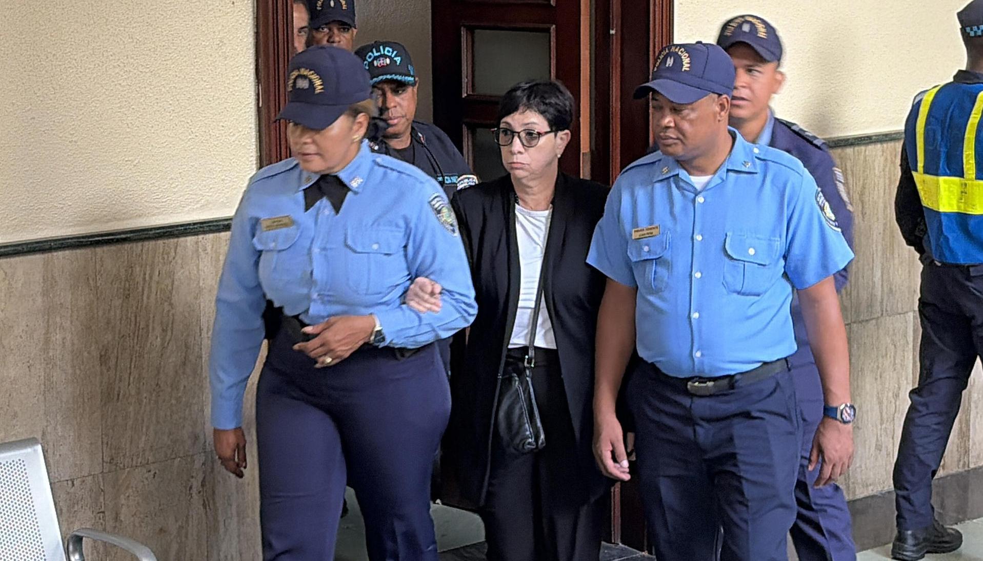 Policías custodian a Maribel Espaillat, a su llegada a la sala de audiencias este viernes en Santo Domingo.