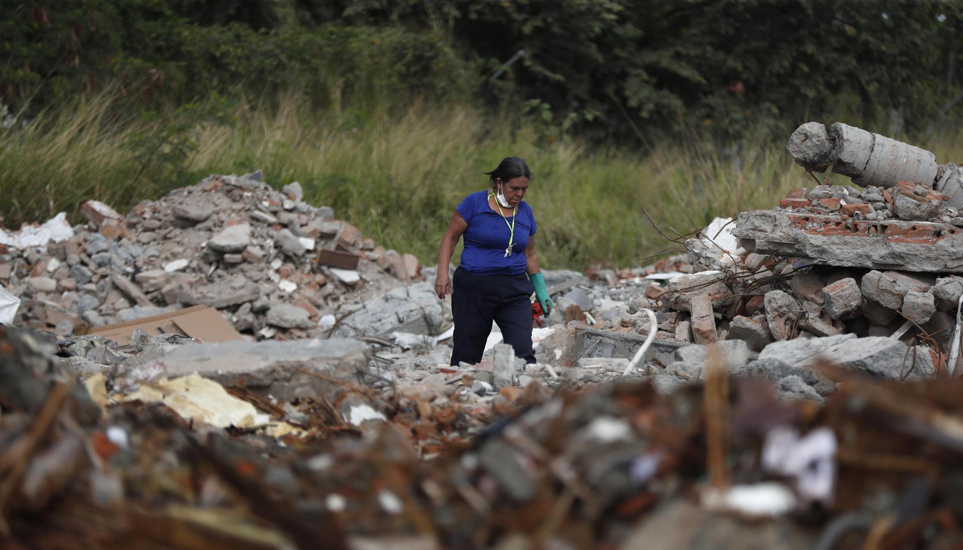 Una persona busca en los escombros de edificios colapsados.