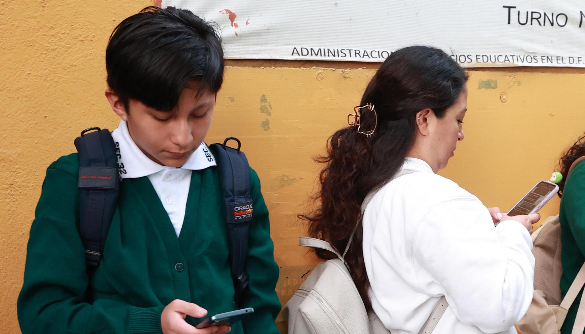 Un estudiante de secundaria usa el celular.