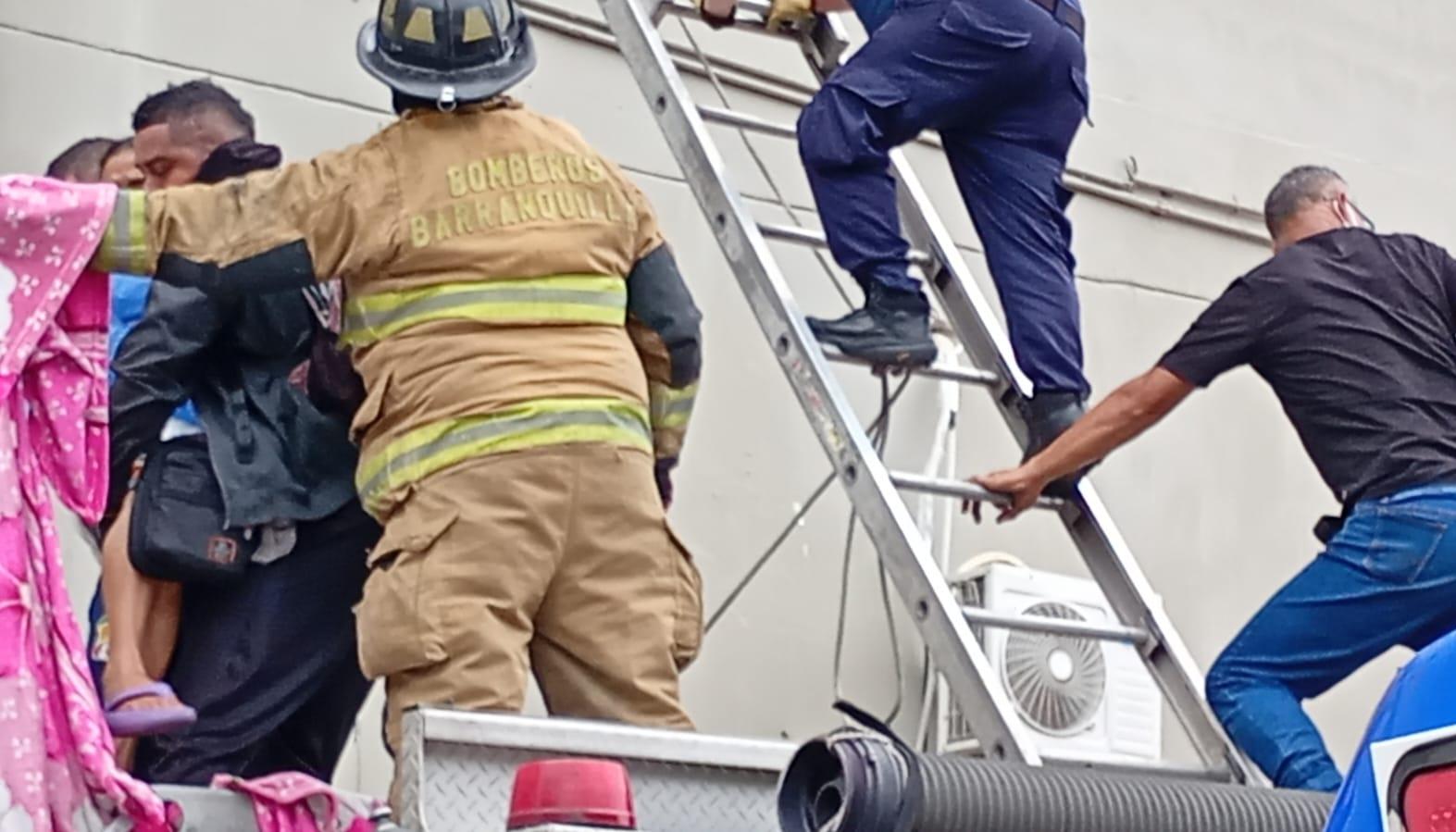 Bomberos con escaleras rescatando pacientes en el tercer piso