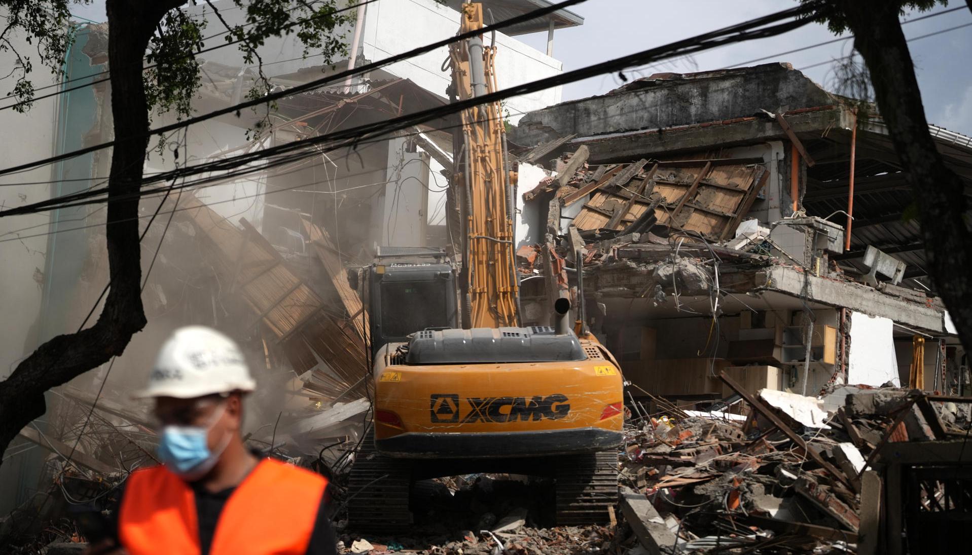 Una retroexcavadora demoliendo un edificio afectado por el terremoto del pasado 10 de agosto, en Cali.