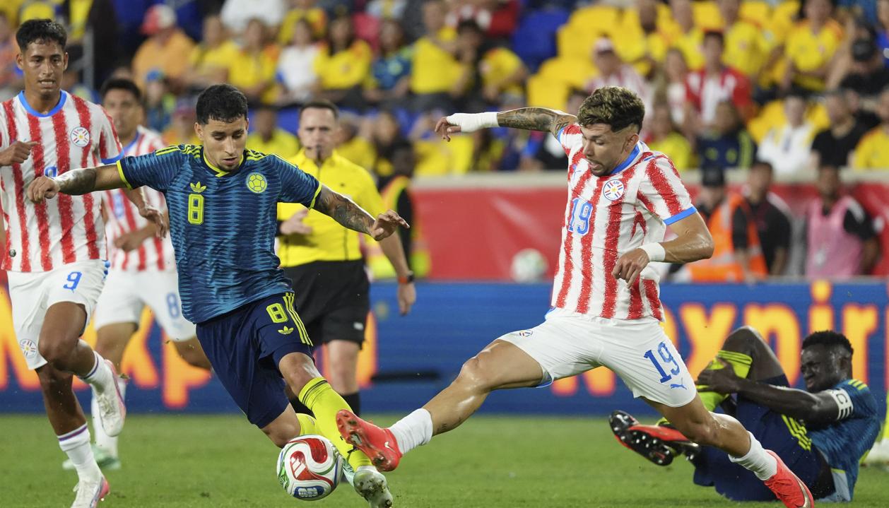 Gustavo Puerta disputa la pelota con el paraguayo Julio Enciso.