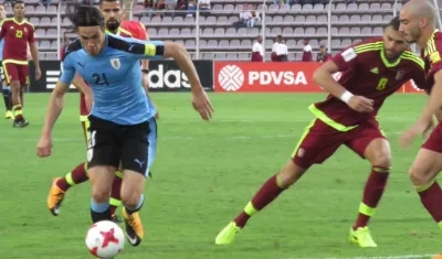 Edinson Cavani intenta eludir la marca de dos venezolanos.