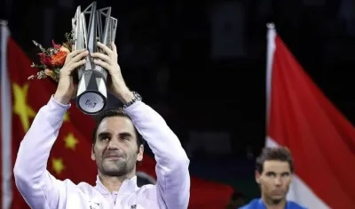 Roger Federer levanta el trofeo ante la mirada de Rafael Nadal.