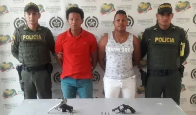 Los dos hombres capturados con las dos armas decomisadas.