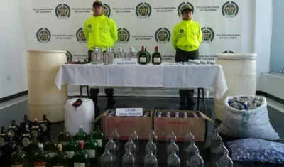 Policías muestran parte del licor adulterado decomisado.